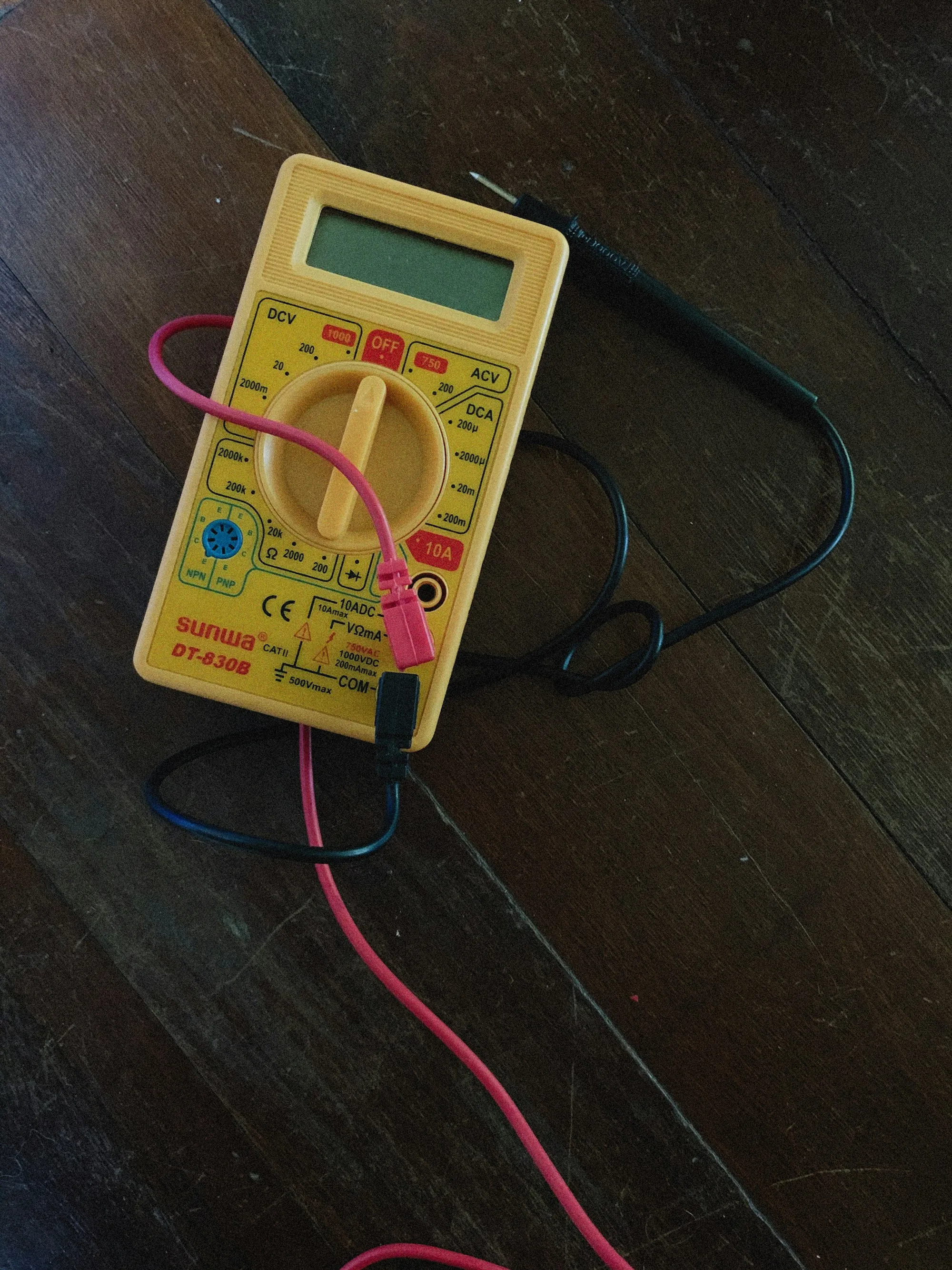 Yellow multimeter with test leads on a dark surface